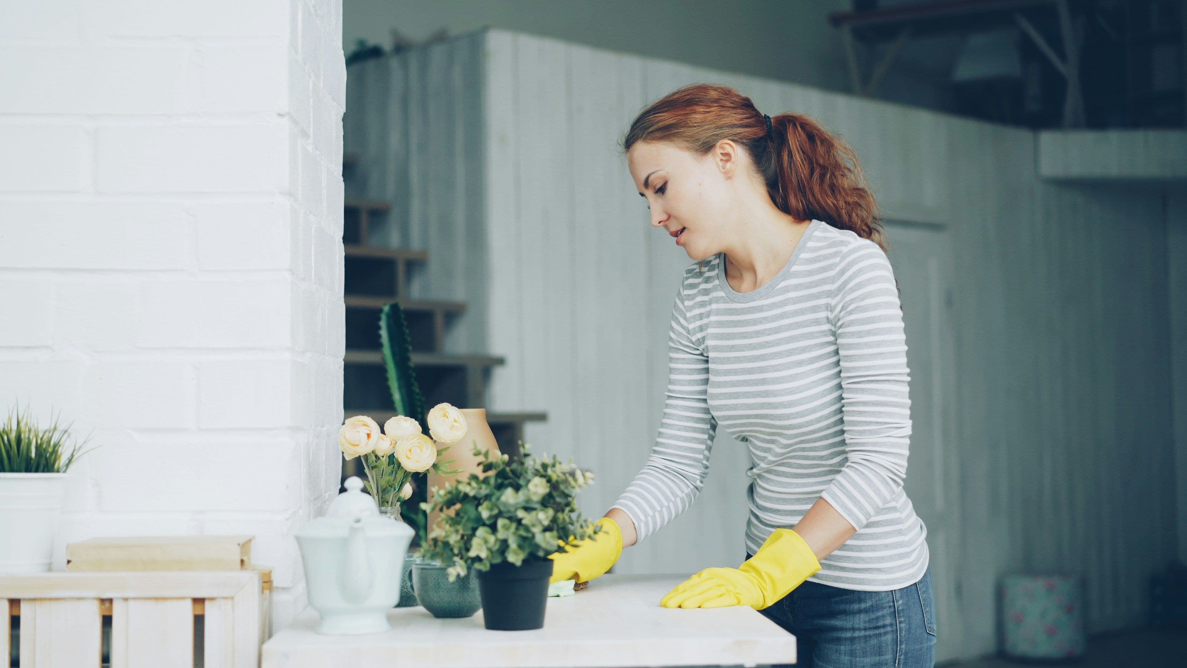 Woman wearing rubber gloves and cleaning table