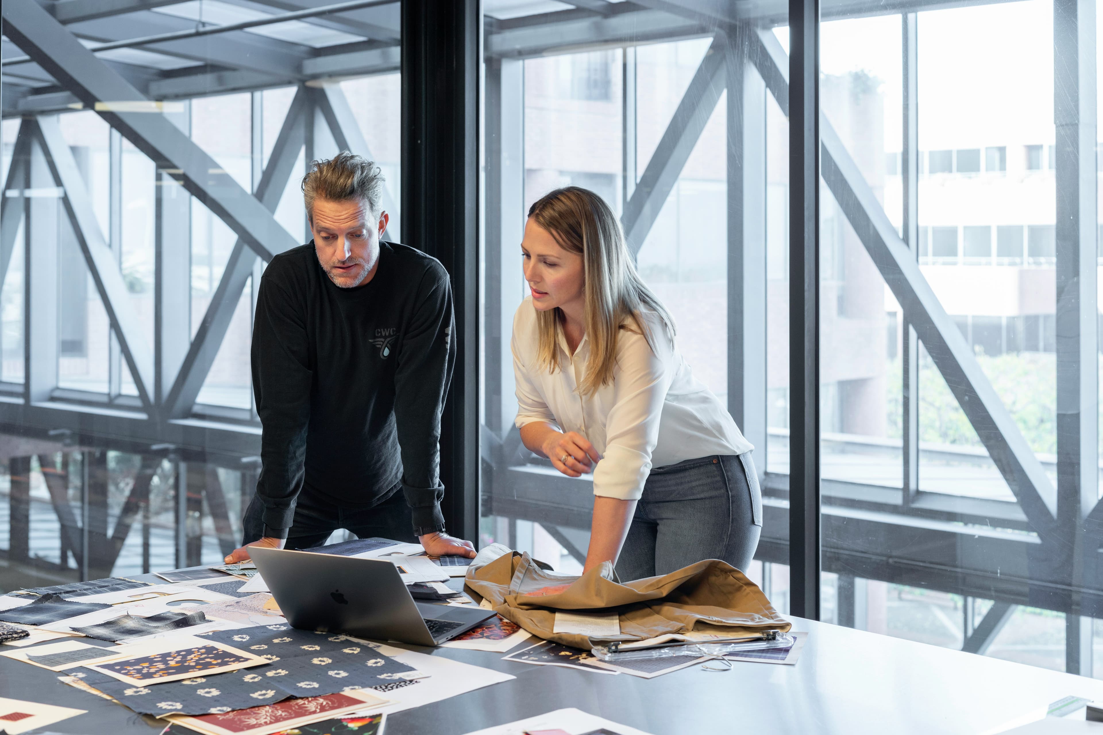 Man and woman standing in office, looking at computer screen